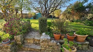 Ein Garten mit Steinmauern, Blumentöpfen und einer kleinen Gartenhütte.