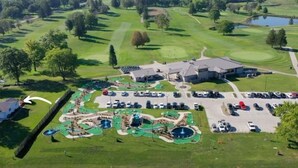 Luchtbeeld van een golfbaan met een clubhuis, parkeerplaats en een waterpark.