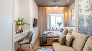 A modern hotel room with a bed, a sofa, a desk with a chair, and a television. - Warsaw Story by StayLab (Warsaw)