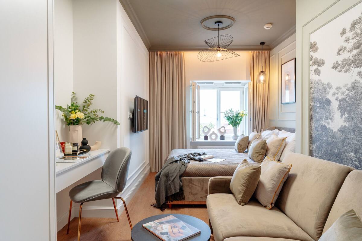 Una habitación de hotel moderna con cama, sofá, escritorio con silla y televisor.