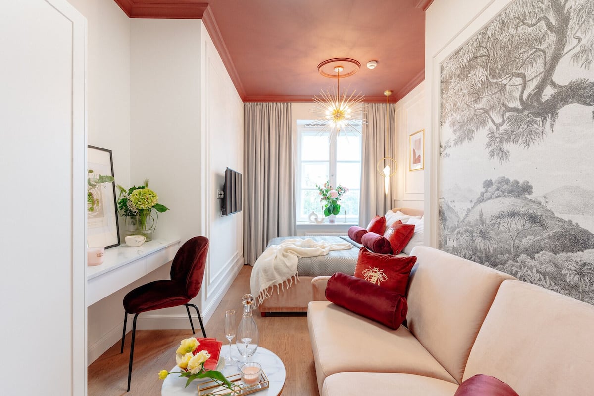 Una sala de estar acogedora con un sofá, un sillón, una mesa de centro y un televisor. Hay una ventana con cortinas y un cuadro en la pared.