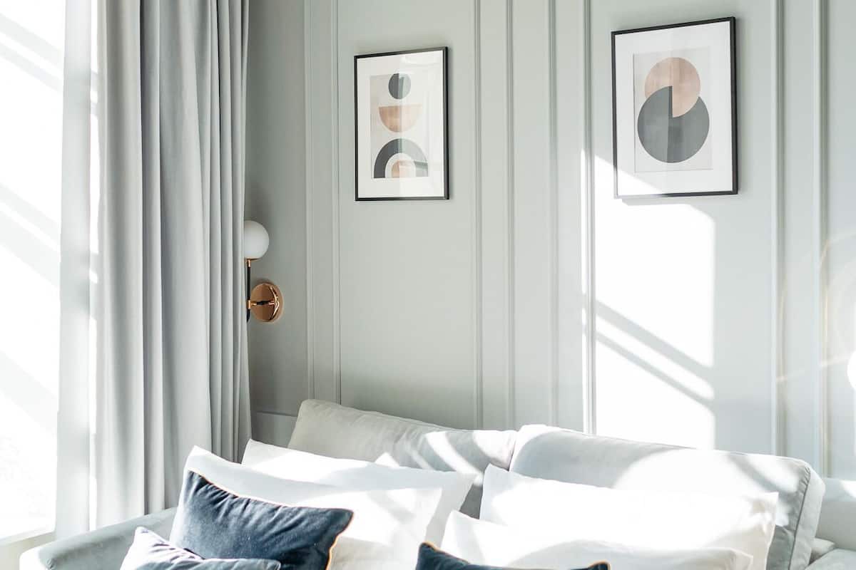 Un dormitorio moderno con cama, almohadas, una lámpara de pared e ilustraciones enmarcadas.