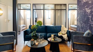 A modern living room with a dark blue sofa, two armchairs, a coffee table with candles, a vase with flowers, and a large mirror reflecting the room. - Warsaw Story by StayLab (Warsaw)