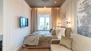A bedroom with a bed, a sofa, a TV, and a window with curtains. - Warsaw Story by StayLab (Warsaw)