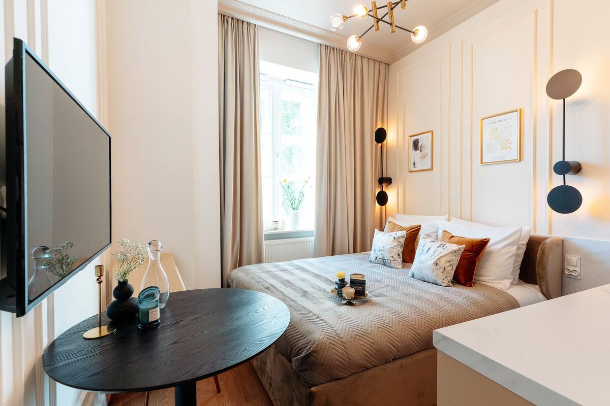 Una habitación de hotel moderna con una cama grande, una mesita de noche y un televisor de pantalla plana.