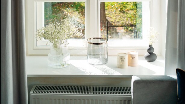 A window with a view of trees and a garden. There are two candles and a vase on the windowsill. - Warsaw Story by StayLab (Warsaw)