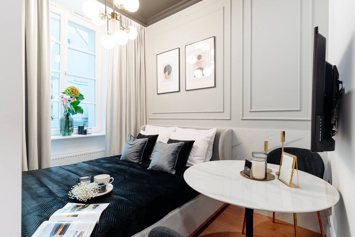 Una habitación de hotel moderna con cama, mesita de noche y ventana con cortinas.