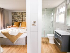Une chambre d’hôtel moderne équipée d’un lit, d’un plateau de petit-déjeuner et d’une salle de bain avec douche, toilettes et lavabo.