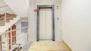 Una scala che conduce a un ascensore, con ringhiera in metallo e un segnale rosso con la lettera X sopra.