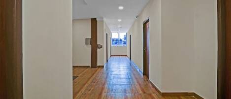 A long, narrow hallway with wooden flooring and white walls.