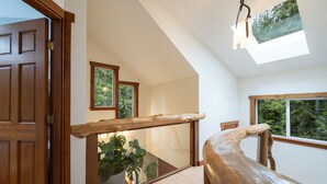 Een houten trap met glazen balustrade, een houten deur en een dakraam.