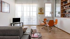 Una sala moderna con un sofá, un televisor y un comedor con sillas y una mesa.