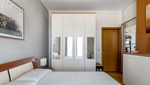 Un dormitorio con cama, armario, espejo y puerta que da a un baño.