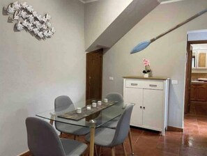 Un coin repas avec une table et des chaises en verre, un meuble blanc et un élément décoratif mural.
