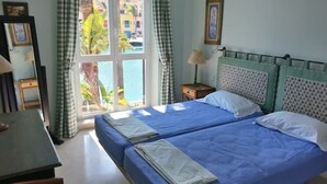 Ein Zimmer mit zwei Betten, einem Schreibtisch und einem fensterbepflanzten Fenster.