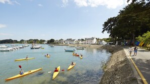 A calm harbor with several kayaks and boats, a stone wall, and a clear sky. - Family stay at 400m from the beach (Sarzeau)