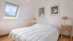 A bedroom with a large bed, a window, two bedside tables, and two framed pictures on the wall. - Family stay at 400m from the beach (Sarzeau)