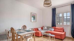A cozy living room with a dining area, featuring a sofa, chairs, a table, and a hanging light fixture. - Family stay at 400m from the beach (Sarzeau)