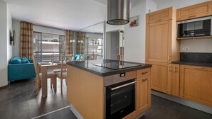 Una cocina moderna con armarios de madera, horno empotrado y campana extractora de acero inoxidable.