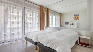 Un dormitorio con una cama, una mesita de noche, un espejo y un cartel en la pared.