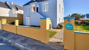 A residential house with a blue exterior, a front porch, and a gated entrance. - Duo vacation near the sea (Le Guilvinec)