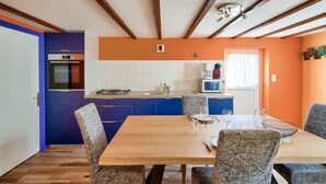 A modern kitchen with blue cabinets, a wooden dining table, and chairs. - Duo vacation near the sea (Le Guilvinec)