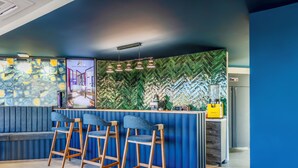 Un área de bar moderna con disposición de asientos azules y una pared con motivo de espiga.