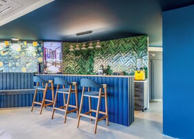 Un área de bar moderna con disposición de asientos azules y una pared con motivo de espiga.
