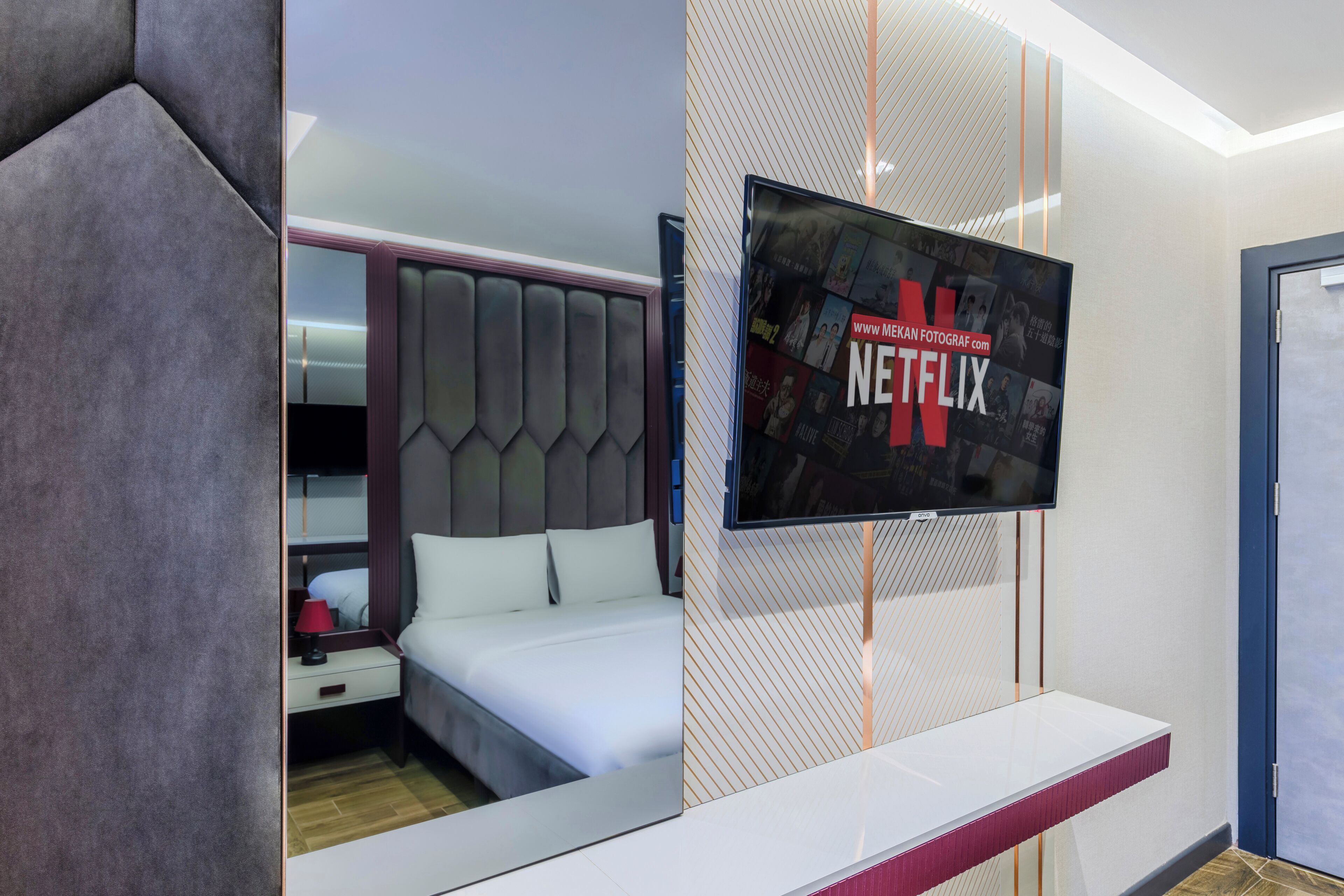 Ein modernes Hotelzimmer mit Bett, Wandfernseher und Nachttisch.