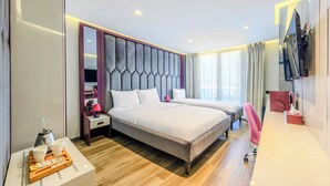 Una habitación de hotel moderna con una cama grande, una mesita de noche con lámpara, televisión y un escritorio con silla.