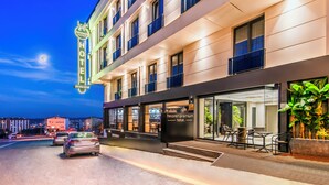 Un hotel con fachada moderna, entrada visible y zona de estar al aire libre.