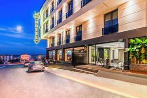 Un hotel con fachada moderna, entrada visible y zona de estar al aire libre.