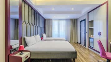Ein Hotelzimmer mit einem großen Bett, einem Schreibtisch mit Lampe, einem Sessel, einem Kleiderschrank und einem Spiegel.
