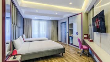 A modern hotel room with a large bed, a desk with a chair, a TV, and a large mirror.