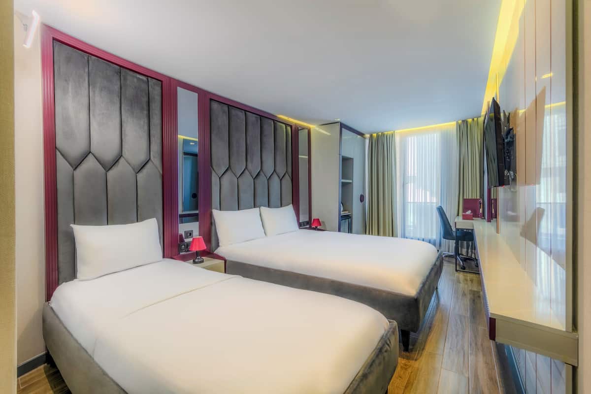 A hotel room with two beds, a desk, and a chair.