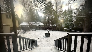 A snow-covered outdoor area with a wooden deck and a metal fence leading to a building. - Knotty Pine Tavern-BBC (Big Bear)