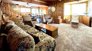 A cozy cabin interior with a wooden floor, a sofa, a coffee table, and a ceiling fan. - Knotty Pine Tavern-BBC (Big Bear)