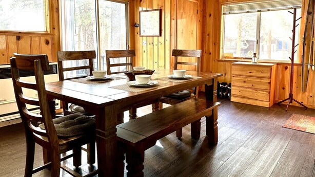 A wooden cabin interior with a dining table, chairs, and a bench. - Knotty Pine Tavern-BBC (Big Bear)