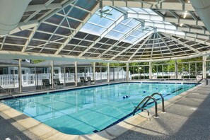 A covered swimming pool with clear glass ceilings, lounge chairs, and a poolside deck. - 3 Bedroom 2.5 bath end unit Townhome in The Salt Pond Community near Bethany Beach (Bethany Beach)
