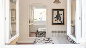 A bedroom with a bed, a mirror, a radiator, and a hanging light fixture.