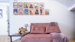 A cozy room with a pink sofa, a small table with a lamp, and a wall decorated with framed artworks. - A garden among vineyards, for 6 (Uruñuela)