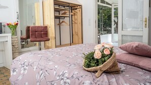 A bedroom with a floral bedspread, a wooden wardrobe, a chair, and a basket of flowers. - A garden among vineyards, for 6 (Uruñuela)