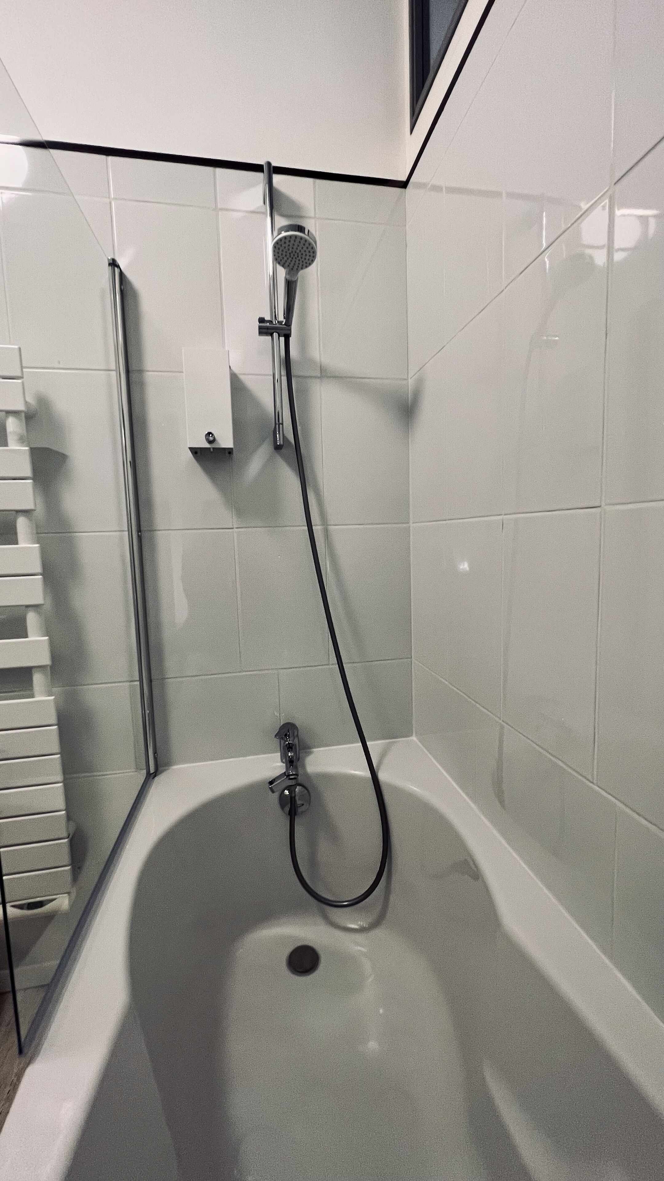 Une douche d’angle équipée d’un pommeau de douche à main et d’un flexible à main.