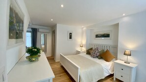 Ein Schlafzimmer mit Bett, Nachttische, Spiegel und Fenster.