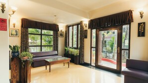 A spacious room with a sofa, a coffee table, and a large window with curtains. - Casa De Cris (Cavelossim)