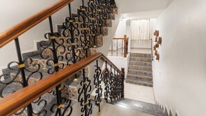 A staircase with ornate black railings and wooden handrails, leading to a room with patterned tiles and a white wall. - Casa De Cris (Cavelossim)
