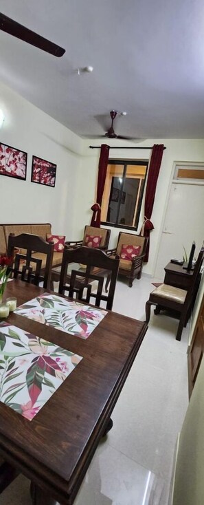 A dining area with a wooden table, chairs, and a ceiling fan. - Casa De Cris (Cavelossim)
