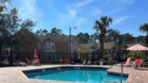 A swimming pool with a hot tub, surrounded by a brick deck and lounge chairs.
