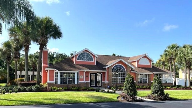 A two-story house with a red facade, a large arched window, and a front porch.