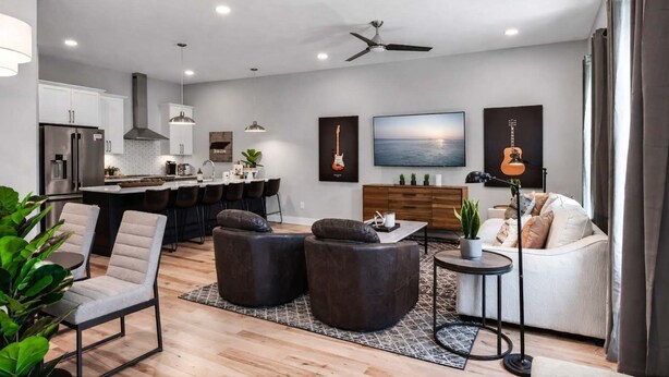 A modern living room with a sofa, armchairs, a coffee table, and a TV.